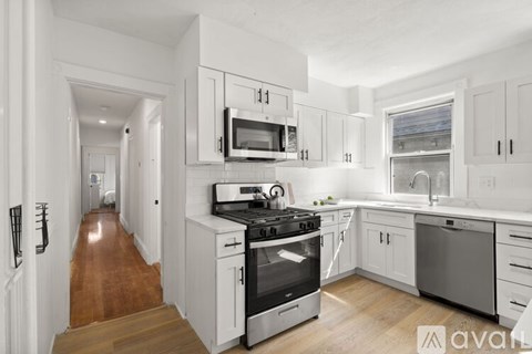 A kitchen with white cabinets and a wooden floor.
