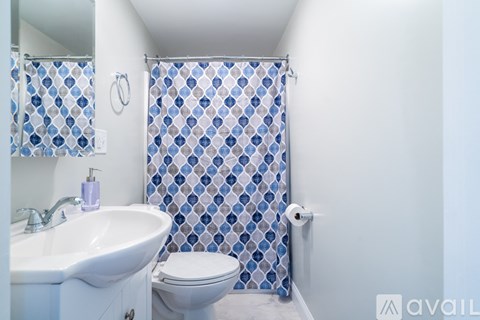 A bathroom with a white sink, toilet and a shower curtain with a diamond pattern.