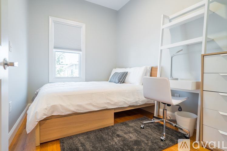 A bedroom with a white bed and a white chair.