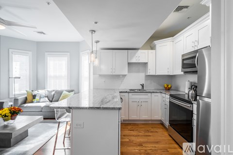 A modern kitchen with white cabinets and a marble island.