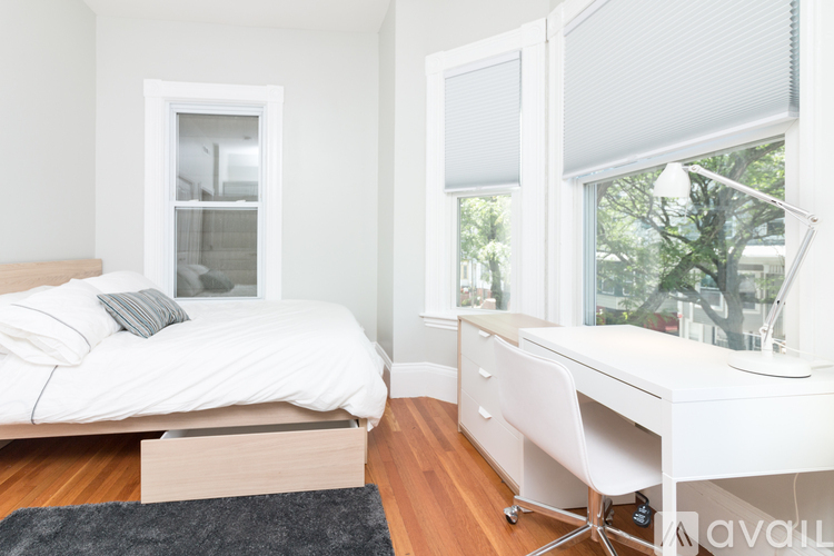 A white bedroom with a bed, desk, and chair.