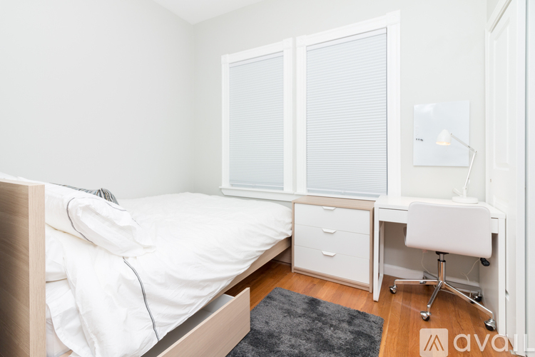 A white bedroom with a bed, desk, and chair.