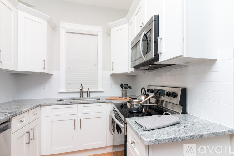 A kitchen with white cabinets and a granite countertop.