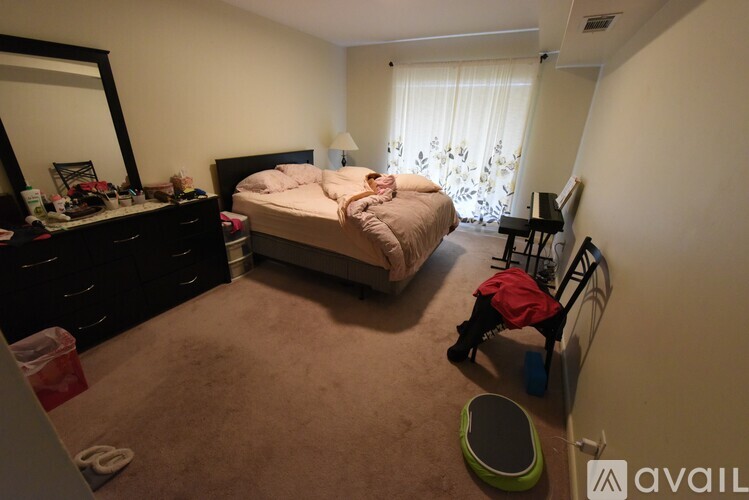 A bedroom with a bed, dresser, mirror, and a window with curtains.