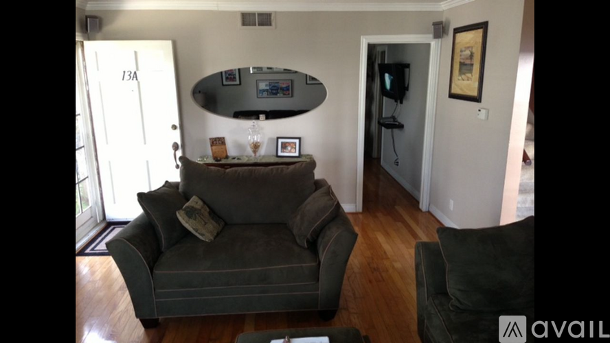 A living room with a grey couch and a TV mounted on the wall.