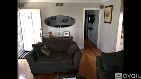 A living room with a grey couch and a TV mounted on the wall.
