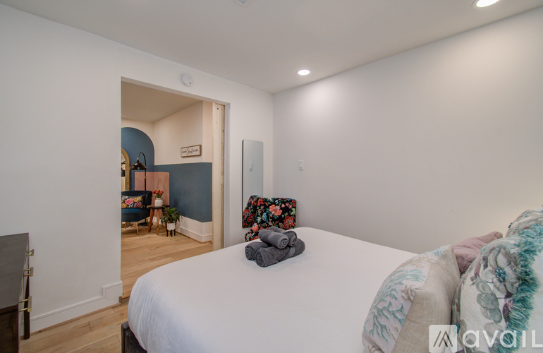 A bedroom with a large bed and a chair in the corner.