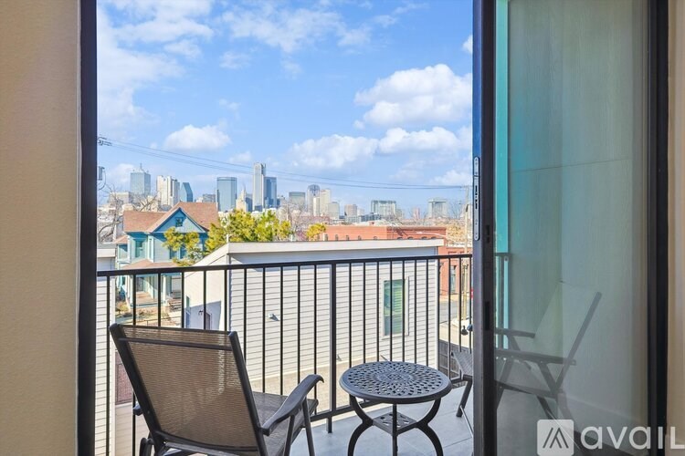 A balcony with a table and chairs overlooking a city skyline.