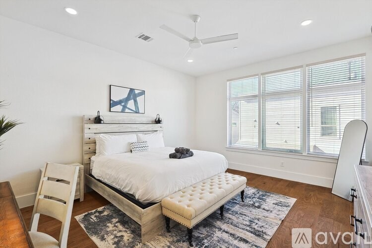 A bedroom with a large bed, a ceiling fan, and a rug.