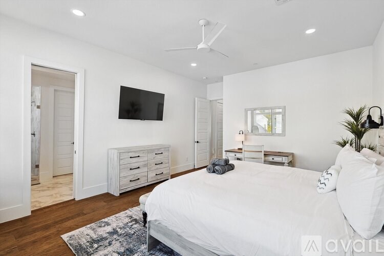 A bedroom with a large bed, a flat screen TV, and a ceiling fan.