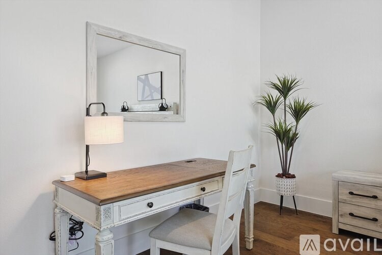 A white desk with a mirror and a plant on the side.
