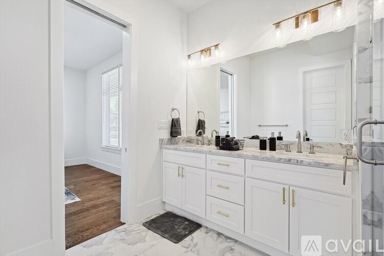 A bathroom with a marble countertop and white cabinets.