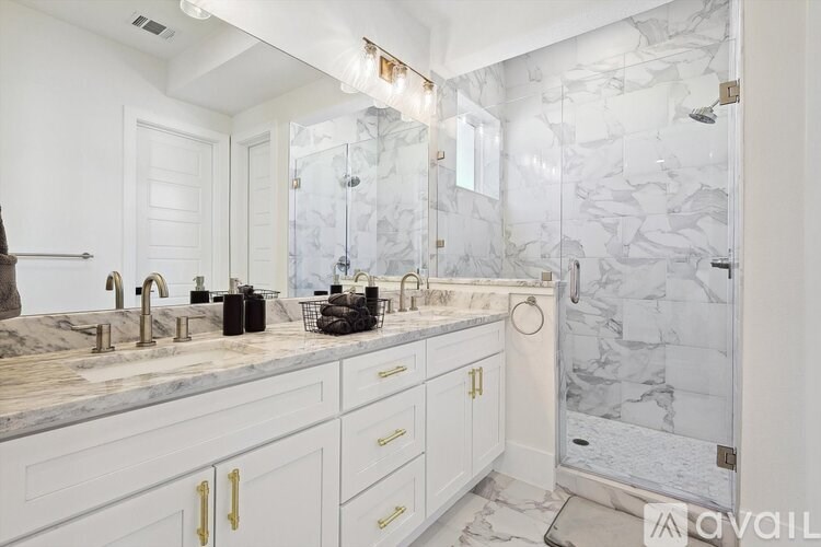 A bathroom with marble tiles and white cabinets.