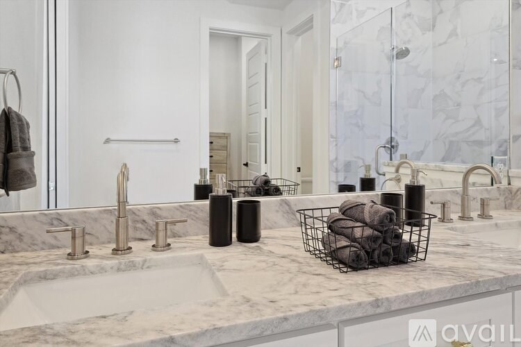 A bathroom with a marble countertop and a basket of towels.