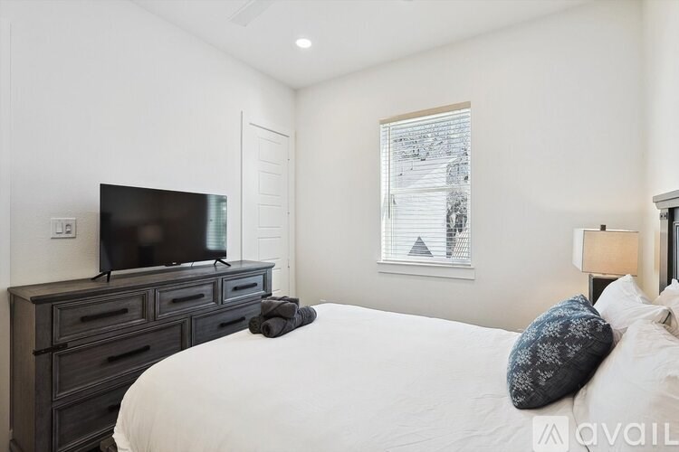 A bedroom with a large bed, a television, and a window with a framed picture.