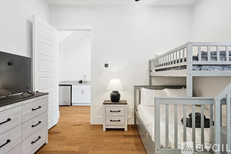 A white bedroom with a bunk bed and a television.