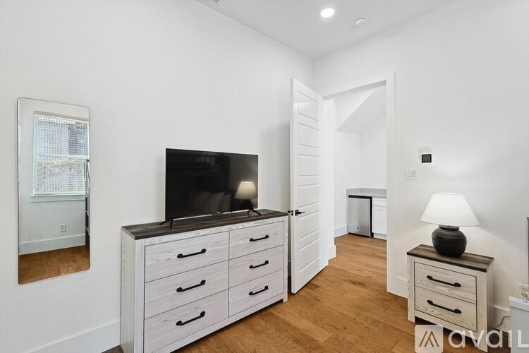 A white room with a television and wooden drawers.
