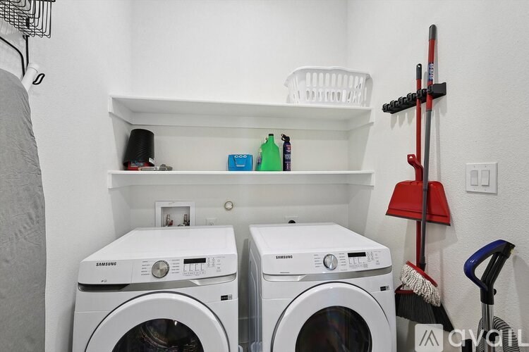 A small laundry room with two washing machines and a red vacuum cleaner.