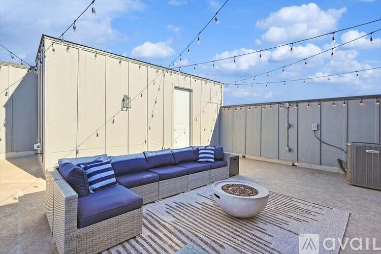 A modern outdoor seating area with a blue couch and a white bowl on a striped rug.