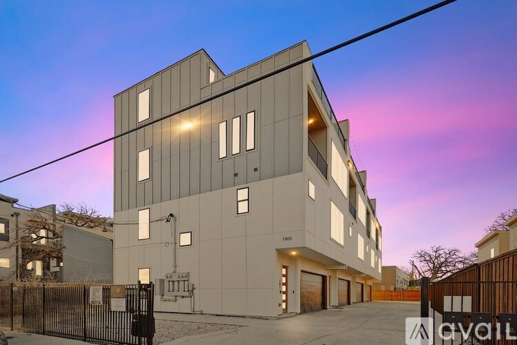A modern building with a flat roof and rectangular windows is illuminated from within.