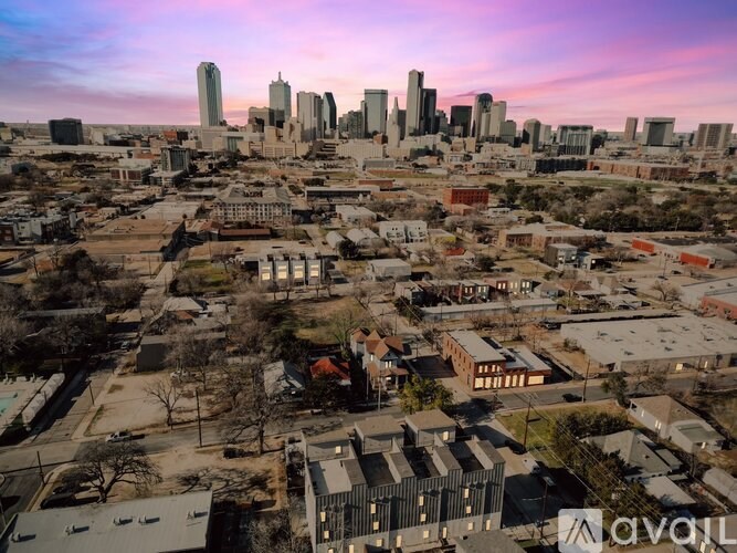 A cityscape with a mix of residential and commercial buildings under a pink and blue sky.