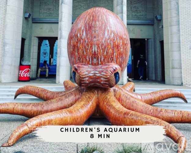 A large octopus statue is in front of a building with a Coca-Cola sign in the background.