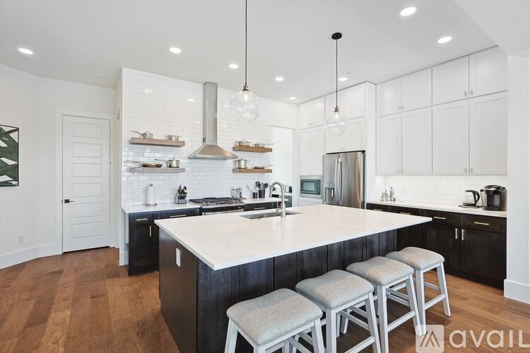 A modern kitchen with a large island and stools.