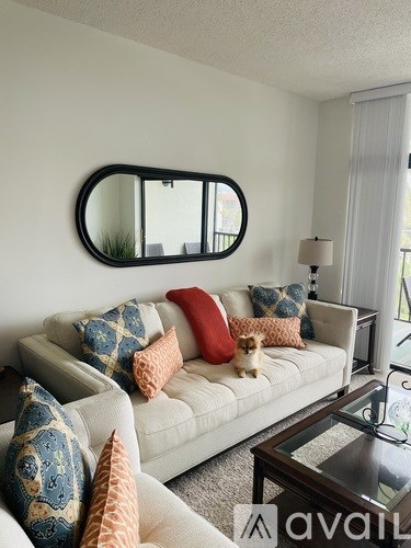 A living room with a white couch and a mirror on the wall.