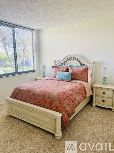 A bedroom with a bed, nightstand, and window.