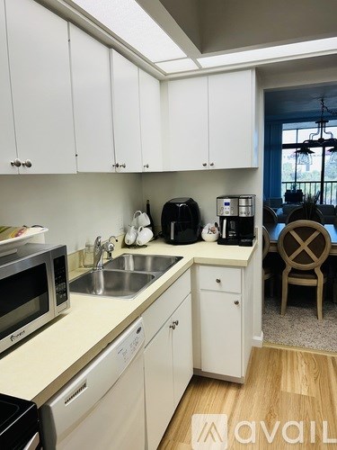 A kitchen with white cabinets and a wooden floor.