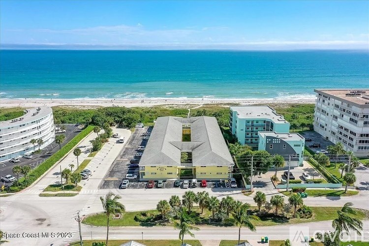 A view of a beachfront area with a building in the foreground and the ocean in the background.