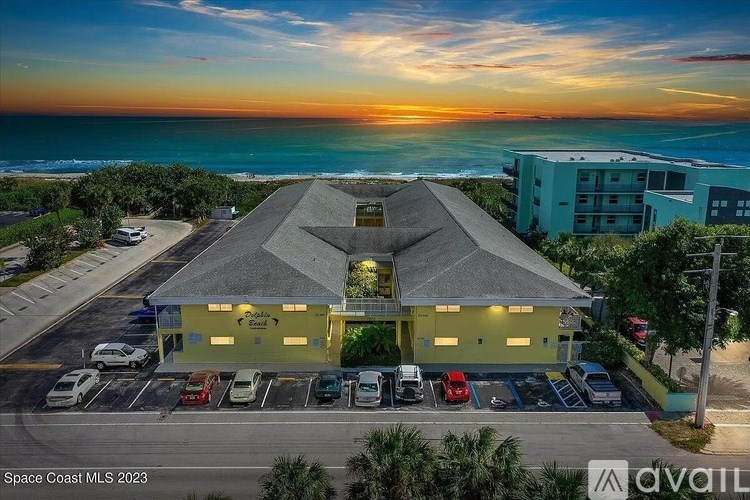 A building with a parking lot in front of it is shown in the image.