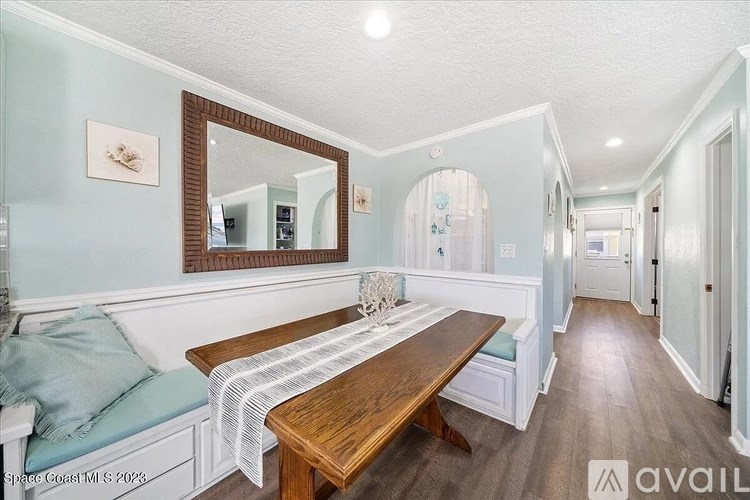 A long wooden table with a white and blue striped table runner is in the middle of a room with a mirror and a couch.