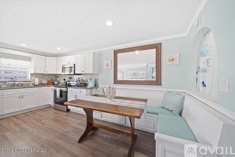 A kitchen with a wooden table and a framed mirror on the wall.