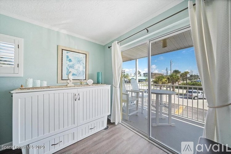 A room with a white cabinet and a glass door leading to a balcony.