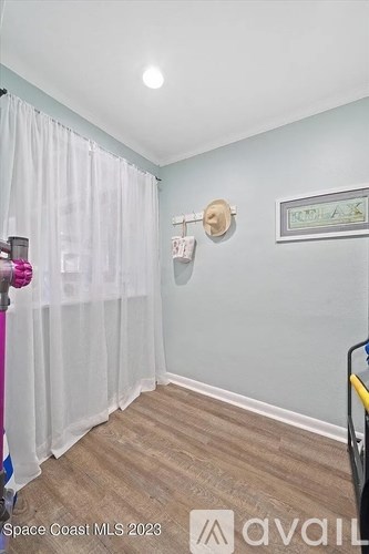 A room with a white curtain and a hat hanging on the wall.