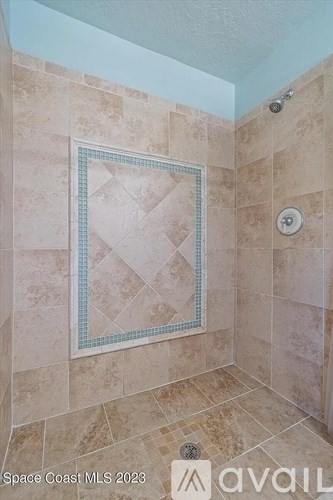 A tiled shower with a diamond pattern bordered by blue tiles.