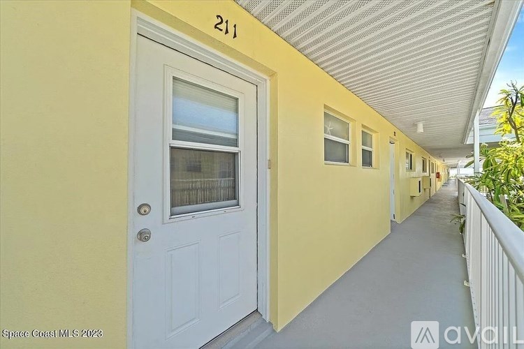 A white door with a window is on the left side of a yellow wall.