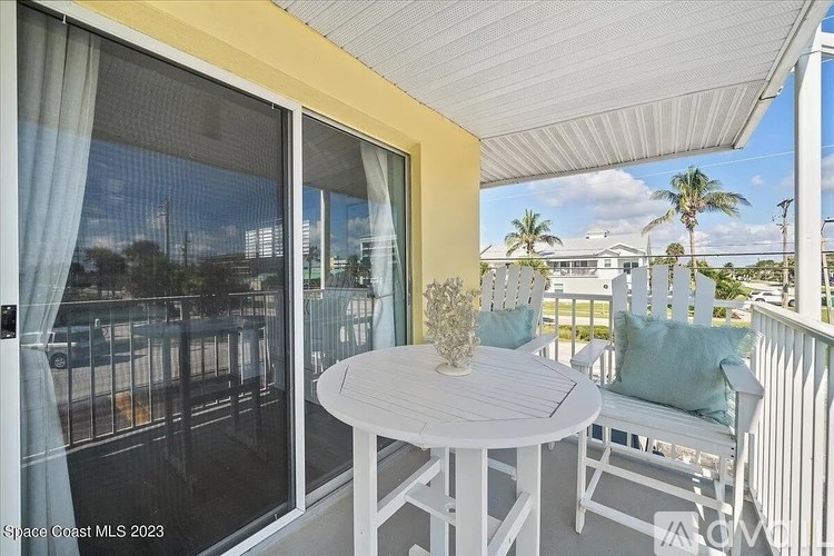 A balcony with a table and chairs overlooking a street.