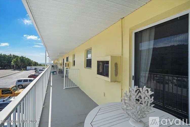 A balcony with a table and chairs overlooking a parking lot.