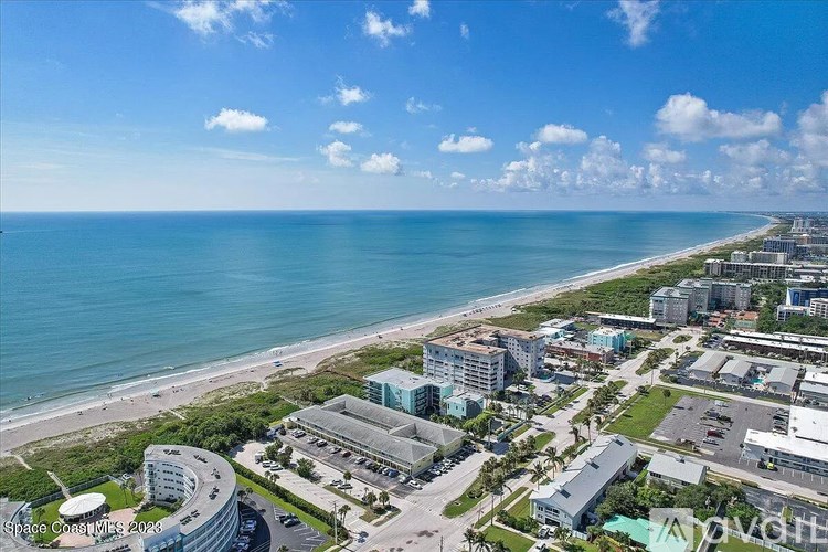A coastal cityscape with a clear blue sky and a large body of water.