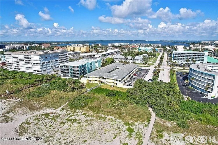 A bird's eye view of a coastal area with buildings and a road.