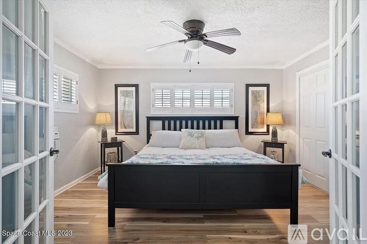 A bedroom with a bed, two lamps, and a ceiling fan.
