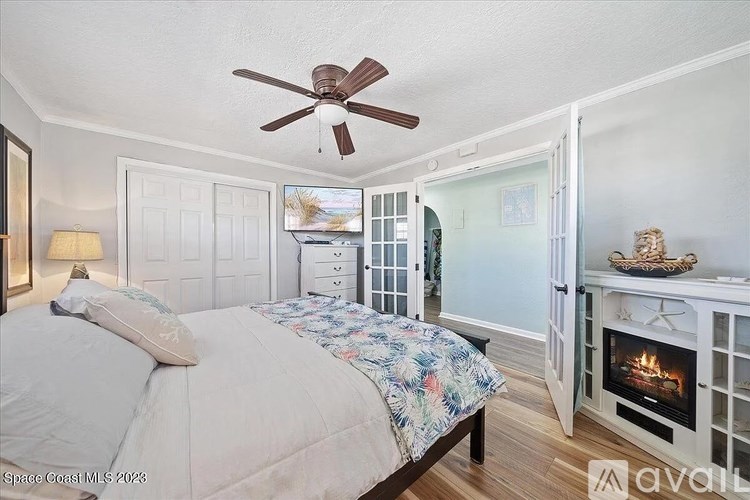 A bedroom with a bed, a fireplace, and a ceiling fan.