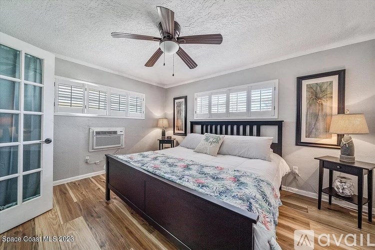 A bedroom with a bed, a ceiling fan, and a nightstand with a lamp.