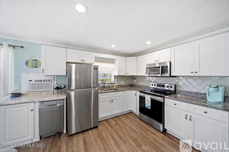 A kitchen with white cabinets and a stainless steel refrigerator.