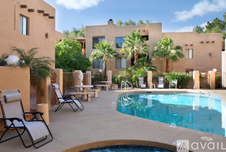 A pool area with lounge chairs and a building in the background.