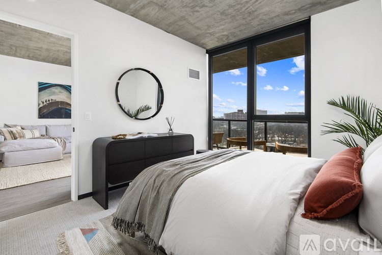 A bedroom with a large bed and a view of the city through the window.