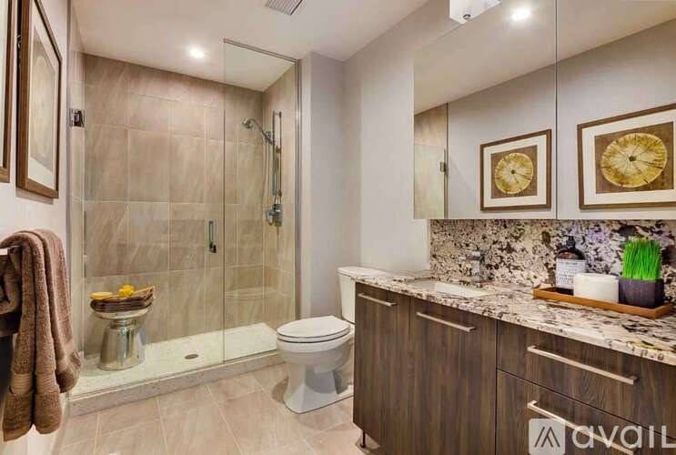 A bathroom with a toilet, a shower, and a towel hanging on the door.