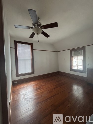 A room with a ceiling fan and wooden floors.